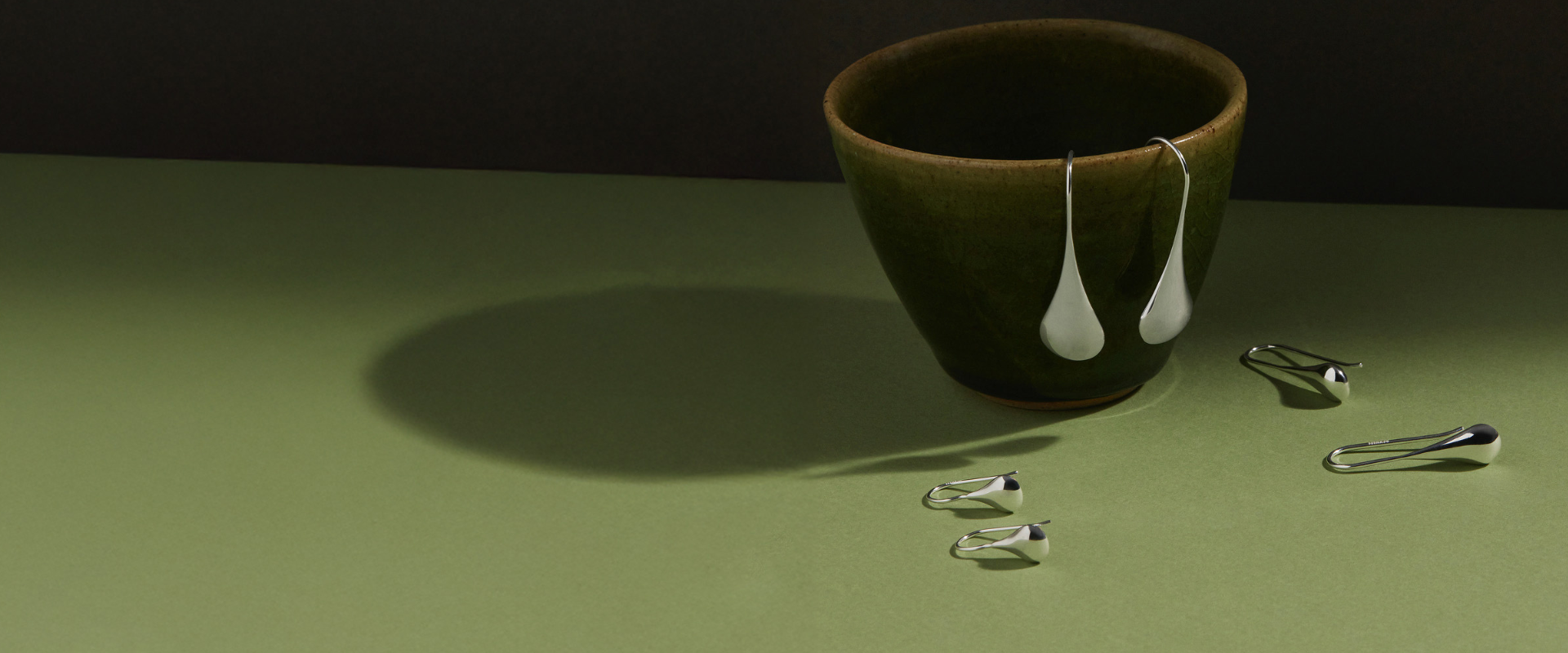 Silver and rose gold pendant earrings on a rock.