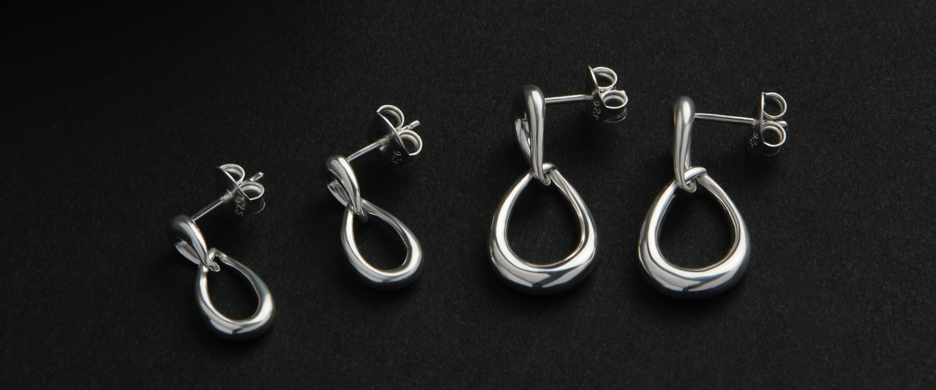 Silver and rose gold pendant earrings on a rock.